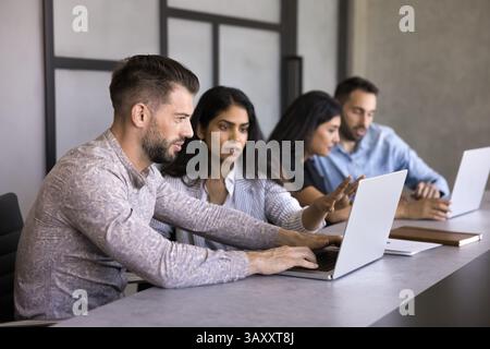 Two multinational workmates using laptop, working on joint tasks Stock Photo