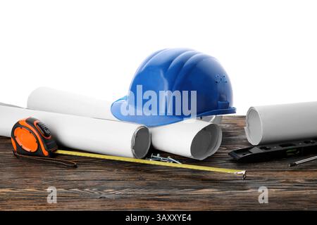 Hardhat, blueprints and construction tools on wooden table against white background Stock Photo