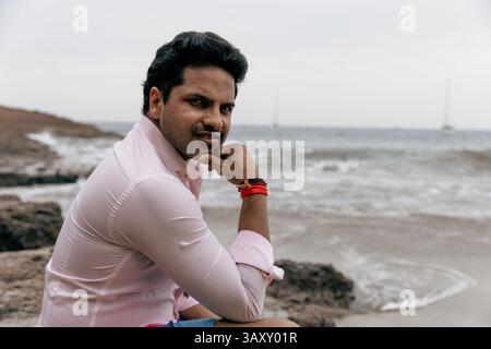 Pensive confident man at the beach wearing a shirt and looking at the camera. Stock Photo