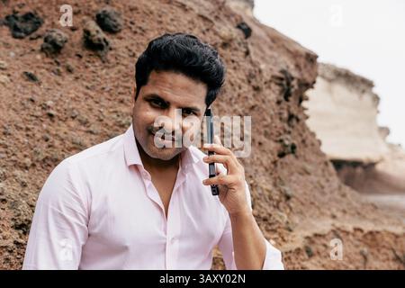Portrait of a man having a phone call outdoors, he is on vacation exploring nature. Stock Photo