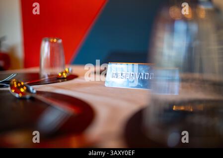 Metal reserved sign placed on elegantly set restaurant table, indicating designated dining space with polished silverware and crystal glassware Stock Photo