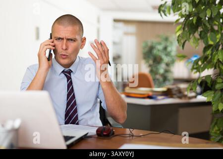 Irritated businessman having difficult phone talk Stock Photo