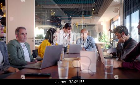 Business team analyzing data on laptops during meeting in modern office Stock Photo