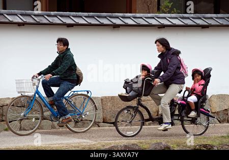 Mother riding behind husband on a bicycle with two children aboard in special front and back seats called mamachari, Hikone, Japan. Stock Photo