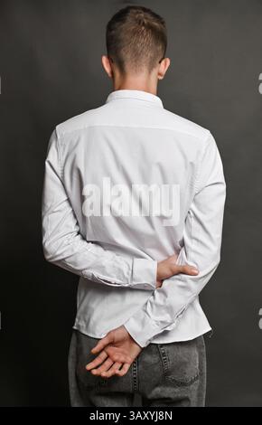 A man's hands clasped behind his back. He wrapped his hand around the wrist of his other hand. Stock Photo