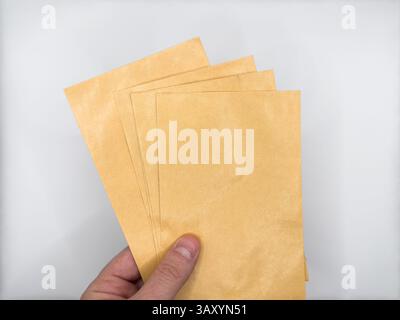 Old yellow envelopes held in hand on white background top view. High quality photo Stock Photo