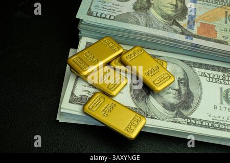 Gold bar and a stack of one hundred dollar bills on a black background representing wealth and financial success Stock Photo