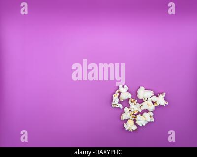 White salted popcorn scattered on purple background right corner bottom view from above. High quality photo Stock Photo