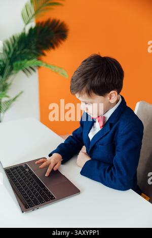 Boy in school uniform working on laptop online Stock Photo