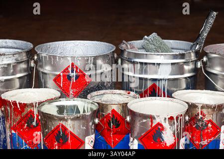Empty paint buckets containing used rollers and brushes. Stock Photo