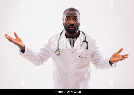 Portrait of serious black male healthcare worker with worried and confused expression gesturing on gray background. Stock Photo