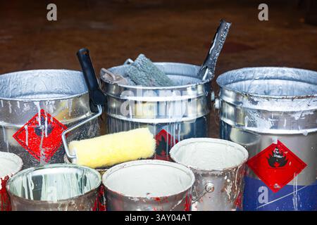 Empty paint buckets containing used rollers and brushes. Stock Photo