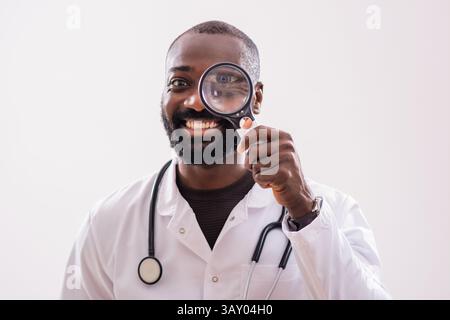 Portrait of African American doctor who is smiling and looking through magnifying glass. Stock Photo