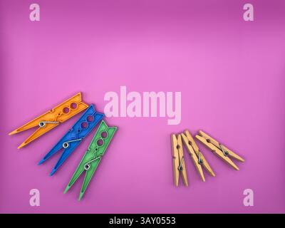 Modern colorful clothes pegs vs old wooden clothes pegs centered on purple background image without unnecessary objects top view. High quality photo Stock Photo