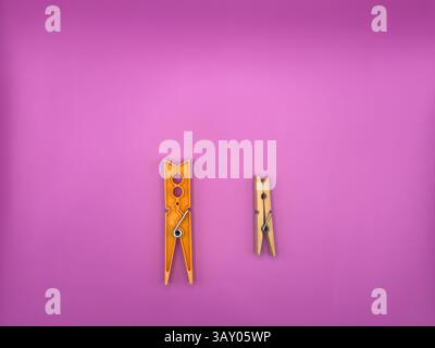 Modern orange plastic clothes peg versus old wooden brown clothes peg centered on purple background image top view. High quality photo Stock Photo
