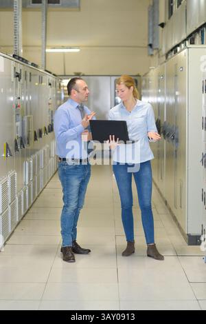 technicians discussing over laptop in server room Stock Photo