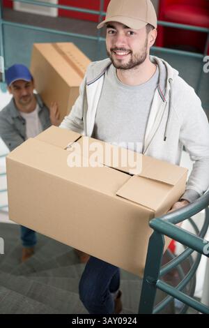 two men carrying boxes up a flight of stairs Stock Photo