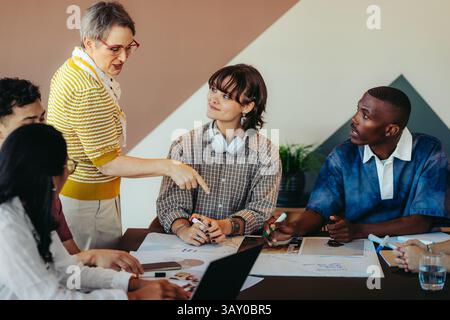 A modern classroom scene with a diverse group of students engaged in discussion, led by an inspiring teacher facilitating collaboration and innovative Stock Photo