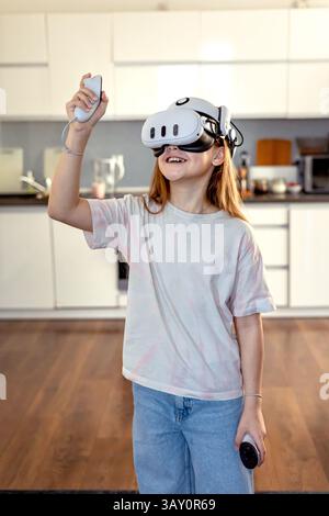 Girl in VR glasses playing a game at home. Learning and playing with augmented reality glasses. Technology and development Stock Photo