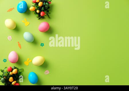 Happy Easter background with colorful Easter eggs and confetti on bright green table. Stock Photo