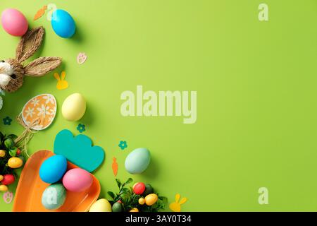 Easter layout with Easter bunny, tulips, colorful eggs on green background Stock Photo