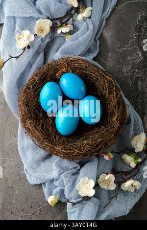 Top view blue Easter eggs in nest with cherry blossoms branches. Stock Photo