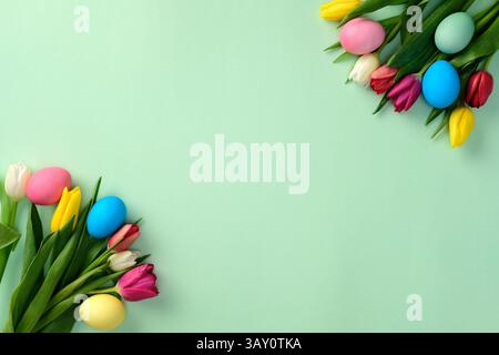 Easter eggs with tulip flowers on green background. Flat lay, top view, copy space Stock Photo