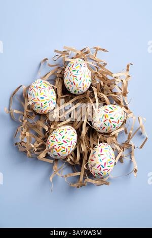 Easter eggs nest on blue background. Flat lay, top view, vertical. Minimal style. Stock Photo