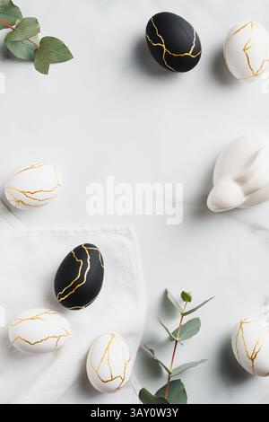 Elegant Easter flat lay composition. Luxury Easter eggs decorated gold, Easter bunny rabbit, eucalyptus on marble table. Top view. Stock Photo