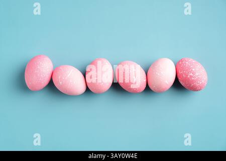 Row of pink Easter eggs on turquoise background. Happy Easter minimal concept. Flat lay, top view. Stock Photo