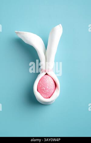 Easter bunny made of pink egg and napkin on turquoise background. Happy Easter concept. Stock Photo