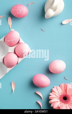 Pink Easter eggs, bunny rabbit, spring flowers on turquoise background. View from above, flat lay. Vertical banner for social media stories. Stock Photo