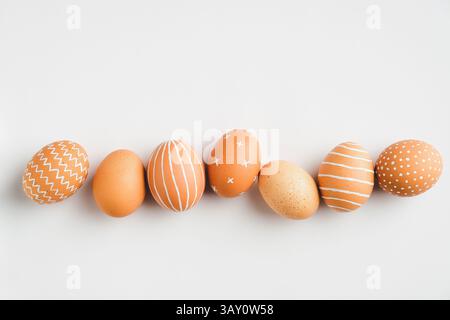 Painted Easter eggs in row on white background. Flat lay, top view. Elegant, simple, modern style. Stock Photo