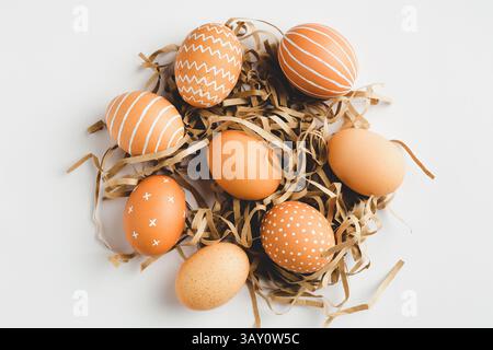 Striped and dotted Easter eggs in nest made of straw. Flat lay, top view. Stock Photo