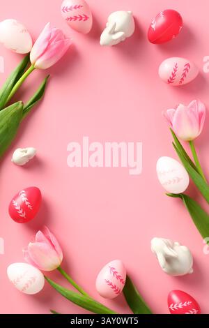Happy Easter poster design, vertical banner template. Frame made of Easter eggs, rabbits, tulips on pink background. Stock Photo