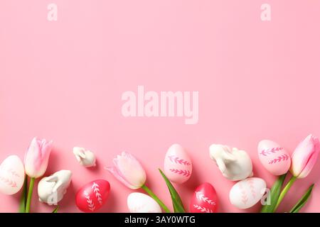 Happy Easter concept. Easter card with colorful eggs, decorative bunnies and tulips on a pink background. Stock Photo