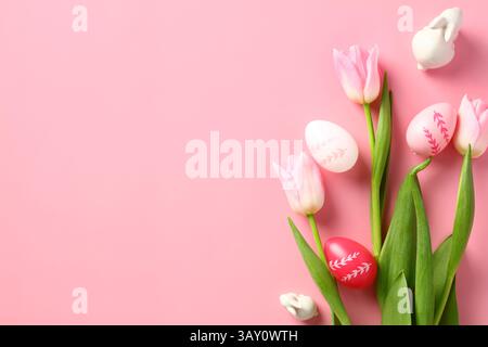 Easter banner design. Colorful Easter eggs, tulips flowers on pink background. Top view, flat lay. Stock Photo