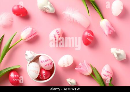 Happy Easter composition. Colorful Easter eggs, tulips, decorative bunnies on pink background. Flat lay, top view. Stock Photo