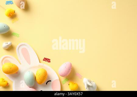Happy Easter creative layout with Easter eggs, decorative chickens, rabbits on pastel yellow table. Stock Photo