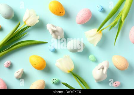 Happy Easter flat lay composition. Easter bunnies and white tulip flowers on pastel blue background. Top view. Stock Photo