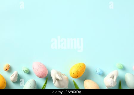 Happy Easter banner template. Frame border made of Easter Eggs, bunny, tulips on light blue table. Flat lay, top view. Stock Photo