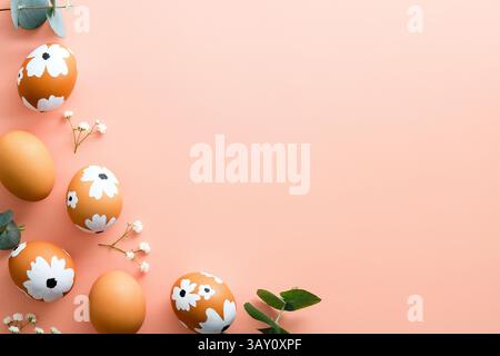 Happy Easter card. Frame made of Easter eggs and spring flowers on pastel pink background. Flat lay, top view, copy space. Stock Photo