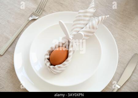 Easter egg with rabbit ears made of napkin on white plate Stock Photo