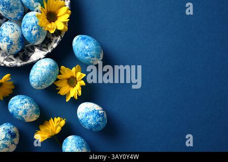 Happy Easter greeting card. Colorful Easter eggs with yellow flowers on dark blue background. Stock Photo