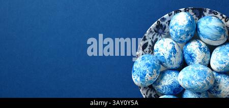 Painted blue Easter eggs on plate on dark blue background. Happy Easter banner template with copy space. Stock Photo