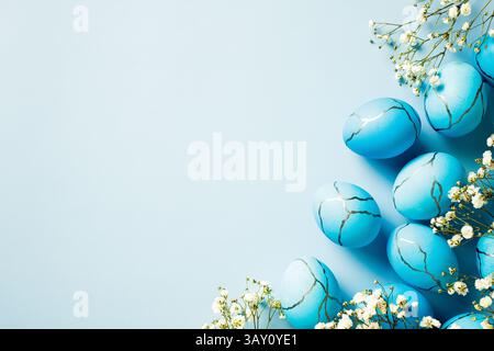 Happy Easter greeting card design. Flat lay dyed blue Easter eggs with flowers on pastel blue background Stock Photo