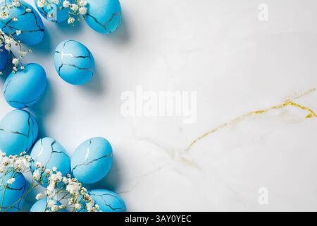 Flat lay composition with blue Easter eggs and flowers on marble stone table. Easter background. Stock Photo