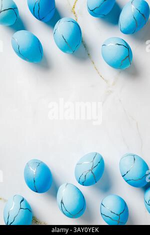 Vertical Easter background. Top view blue painted eggs on marble table. Stock Photo