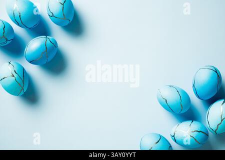 Frame of painted Easter eggs on blue background. Elegant Happy Easter card template. Flat lay, top view, copy space. Stock Photo