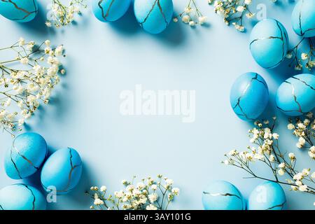 Stylish Easter eggs with white minimal flowers on pastel blue background. Flat lay, top view, copy space. Stock Photo